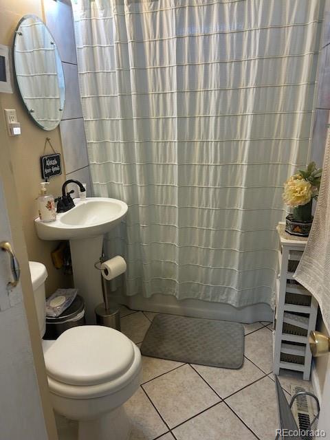 bathroom with tile patterned flooring, shower / bath combination with curtain, and toilet