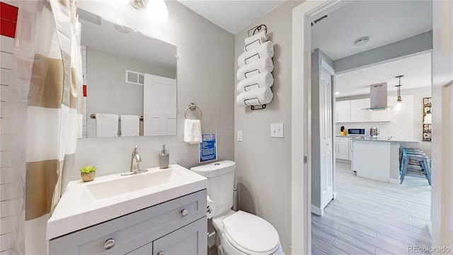 bathroom with hardwood / wood-style floors, vanity, and toilet