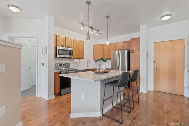 kitchen with light hardwood / wood-style floors, stainless steel appliances, a center island, and hanging light fixtures