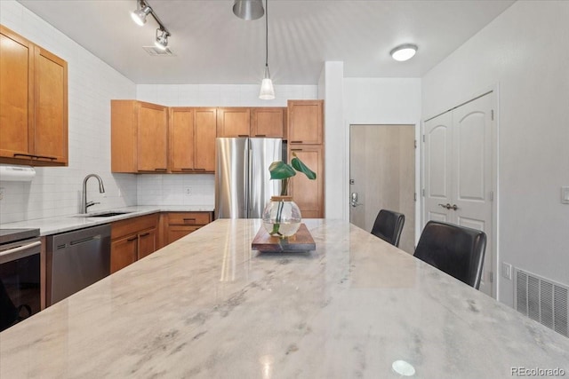 kitchen with stainless steel appliances, light stone countertops, a kitchen bar, sink, and tasteful backsplash