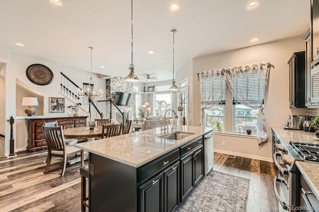 kitchen featuring appliances with stainless steel finishes, sink, dark wood-type flooring, pendant lighting, and a center island with sink