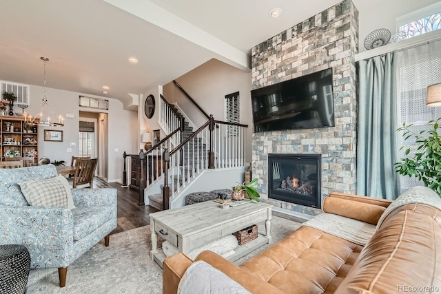 living room with hardwood / wood-style floors, a notable chandelier, and a large fireplace