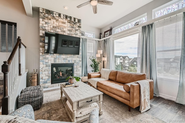 living room featuring ceiling fan, a fireplace, and wood-type flooring