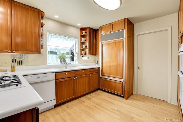 kitchen with open shelves, paneled built in refrigerator, white dishwasher, a sink, and brown cabinets