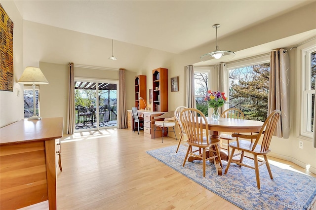 dining area featuring a wealth of natural light, vaulted ceiling, and light wood-type flooring