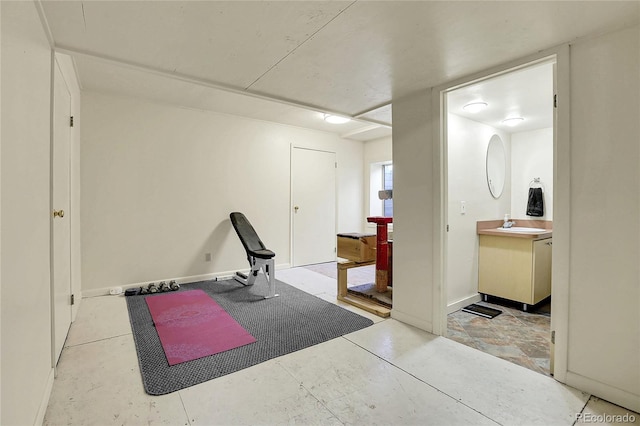 exercise room featuring baseboards and a sink