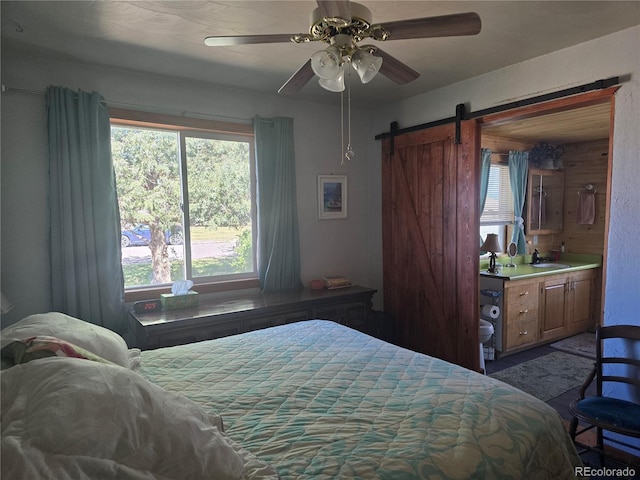 bedroom featuring wooden walls, ceiling fan, sink, and a barn door