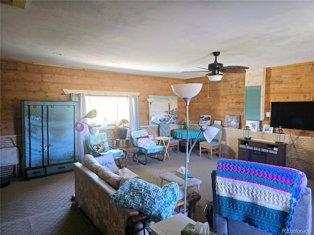 carpeted living room featuring wood walls and ceiling fan