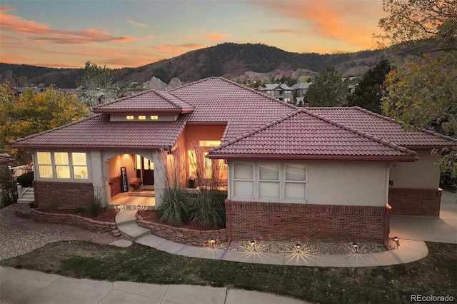 mediterranean / spanish-style home with stucco siding, a tile roof, a mountain view, and brick siding