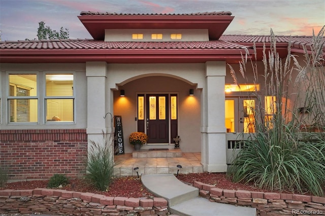 exterior entry at dusk with covered porch and stucco siding