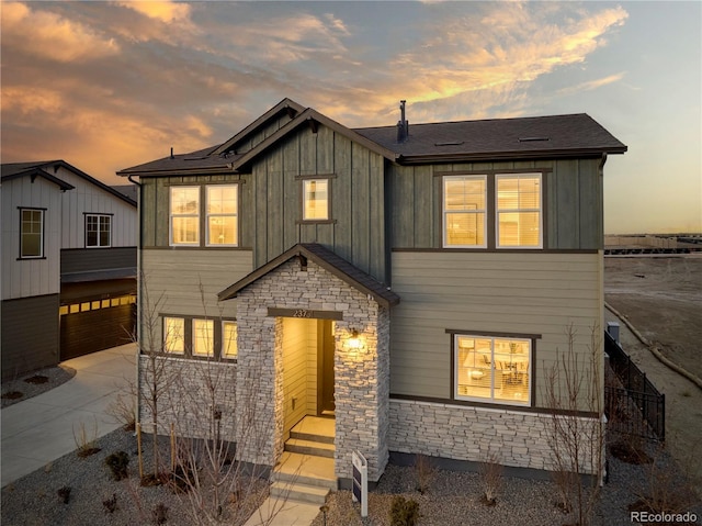 view of front of house with a garage, stone siding, board and batten siding, and driveway