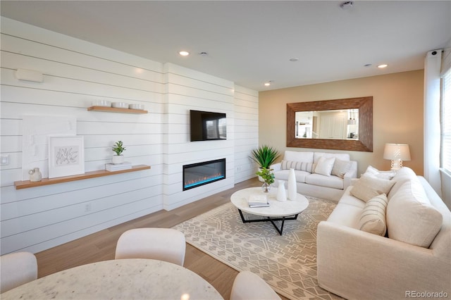 living room featuring a glass covered fireplace, recessed lighting, and wood finished floors