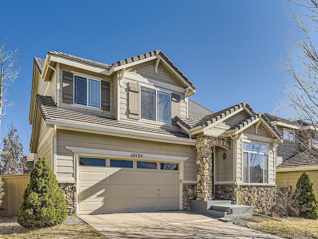 craftsman-style home with a tile roof, concrete driveway, an attached garage, fence, and stone siding