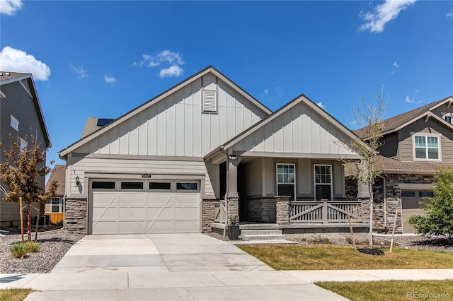 craftsman inspired home with stone siding, board and batten siding, covered porch, and driveway
