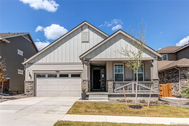 craftsman house featuring stone siding, covered porch, board and batten siding, an attached garage, and concrete driveway