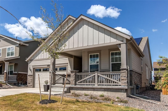 view of front of home with board and batten siding, a porch, stone siding, and a garage