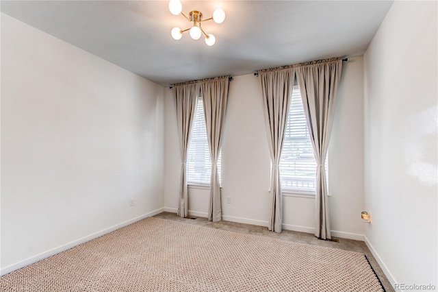 spare room featuring plenty of natural light, light colored carpet, and baseboards