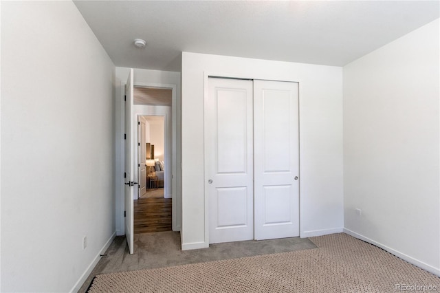 unfurnished bedroom with carpet floors, baseboards, and a closet