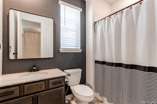 bathroom with toilet, vanity, a textured wall, and a shower with curtain