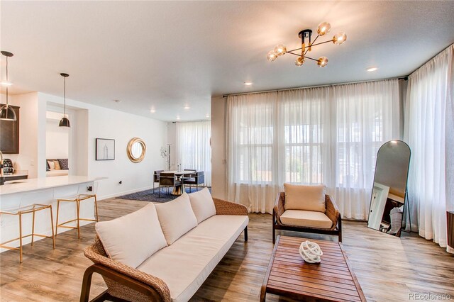 living area with light wood finished floors, a chandelier, and recessed lighting