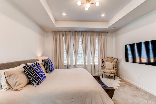 bedroom with a raised ceiling, baseboards, carpet floors, and a chandelier