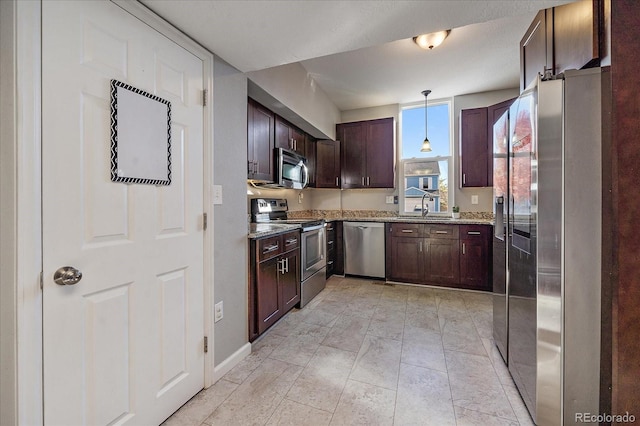 kitchen with sink, light stone countertops, dark brown cabinets, appliances with stainless steel finishes, and decorative light fixtures