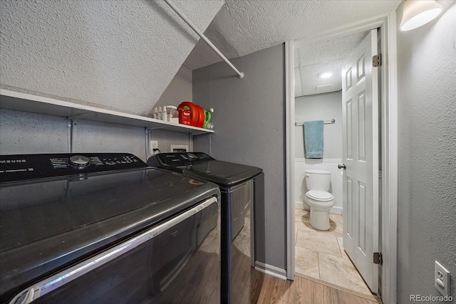 clothes washing area featuring hardwood / wood-style floors, independent washer and dryer, and a textured ceiling