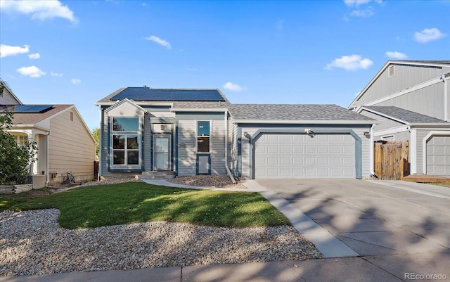 view of front of property with a garage, a front yard, and solar panels