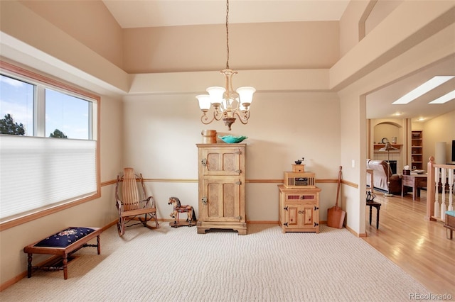 sitting room featuring a skylight, a towering ceiling, carpet flooring, a chandelier, and baseboards