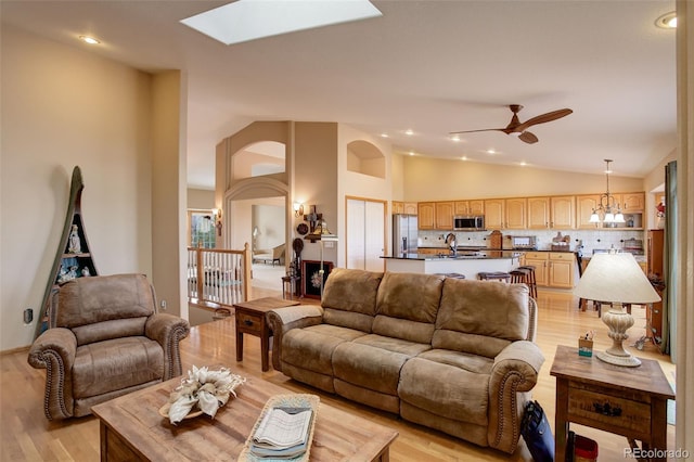 living area featuring a skylight, ceiling fan, light wood-style floors, high vaulted ceiling, and recessed lighting