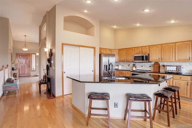 kitchen featuring a breakfast bar, backsplash, stainless steel appliances, and a sink