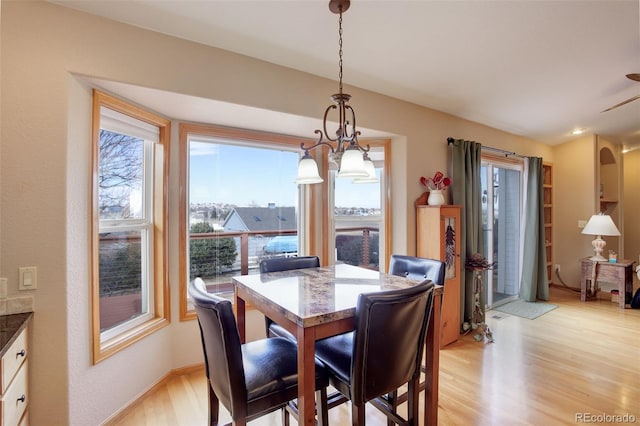 dining area with light wood-style floors, arched walkways, and baseboards