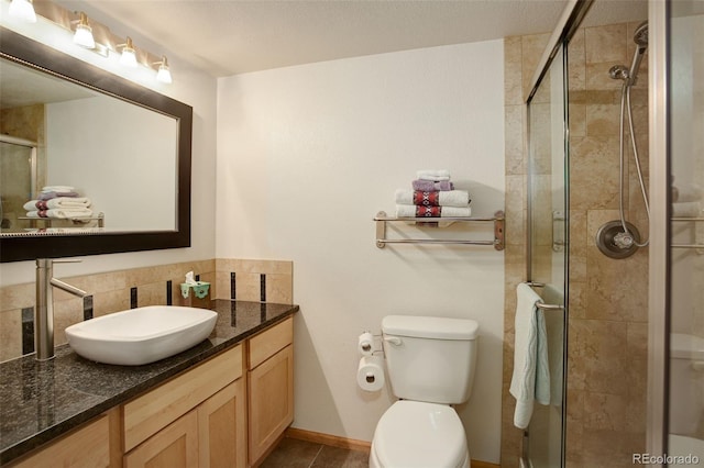 full bath featuring toilet, vanity, baseboards, a shower stall, and tasteful backsplash