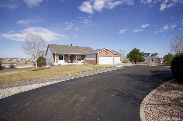 ranch-style house featuring brick siding, a porch, a garage, driveway, and a front lawn