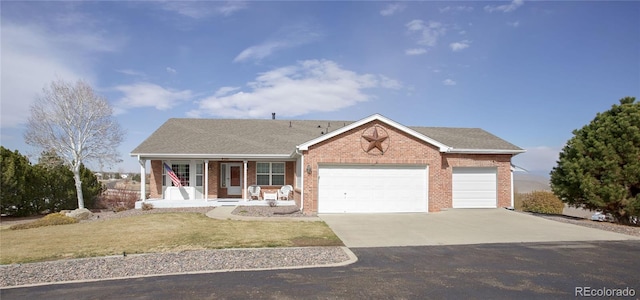 ranch-style home with brick siding, a porch, a garage, driveway, and a front lawn