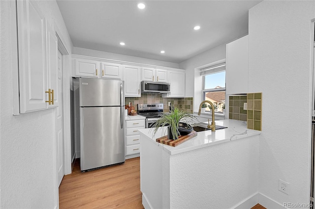 kitchen with backsplash, sink, appliances with stainless steel finishes, light hardwood / wood-style floors, and white cabinetry