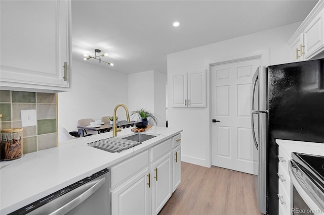 kitchen featuring white cabinets, sink, light wood-type flooring, appliances with stainless steel finishes, and a notable chandelier