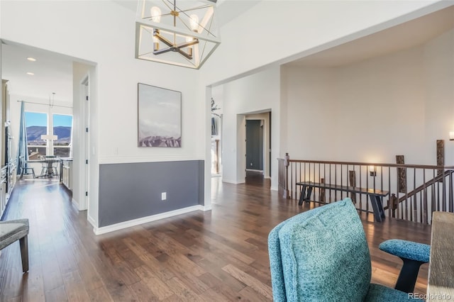 interior space featuring dark hardwood / wood-style flooring, a towering ceiling, and an inviting chandelier