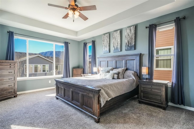 bedroom with a raised ceiling, ceiling fan, carpet, and a mountain view