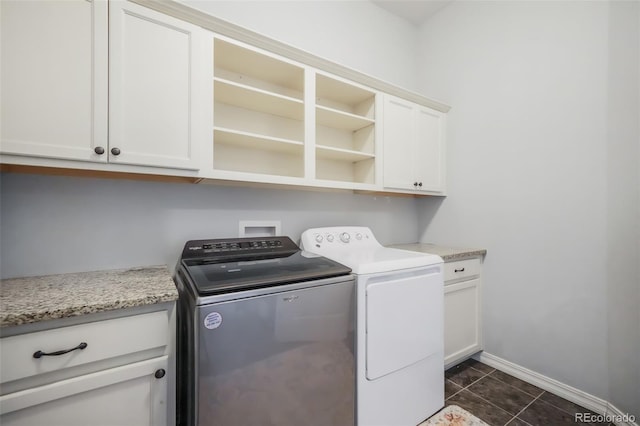 laundry area with washing machine and dryer, dark tile patterned floors, and cabinets