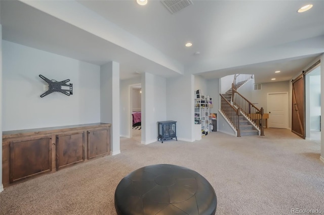 interior space with a barn door, a wood stove, and light carpet