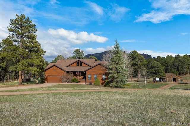 view of front of property with a front lawn, driveway, a mountain view, and a garage