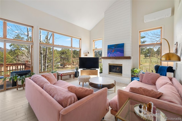 living room with light wood finished floors, a brick fireplace, an AC wall unit, and high vaulted ceiling