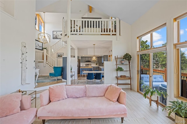 living area with high vaulted ceiling, beam ceiling, stairs, and light wood-style floors