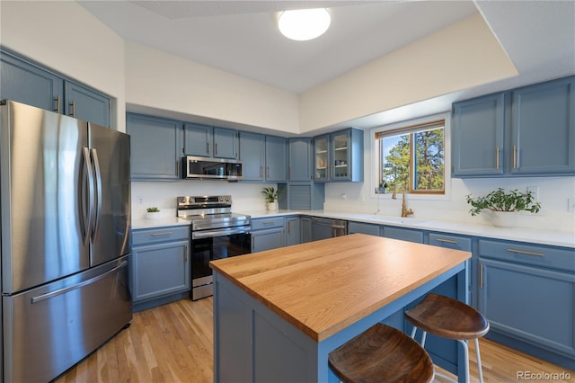 kitchen with blue cabinets, stainless steel appliances, a breakfast bar, and wood counters