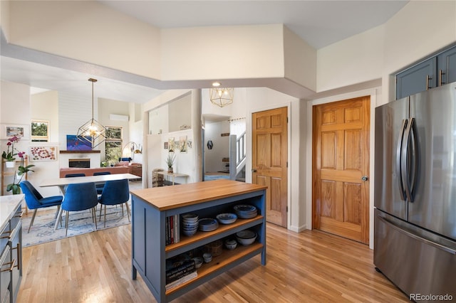 kitchen featuring open shelves, blue cabinets, light wood-type flooring, butcher block counters, and freestanding refrigerator