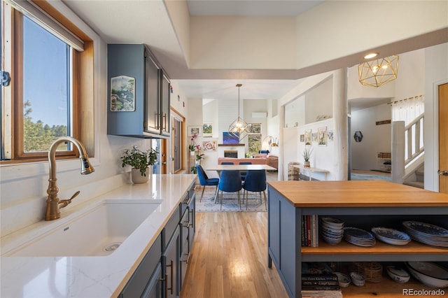 kitchen featuring a sink, gray cabinets, pendant lighting, light wood-style flooring, and blue cabinetry