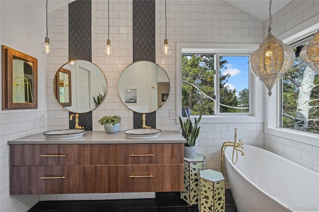 full bath featuring tile patterned floors, a freestanding bath, tile walls, lofted ceiling, and vanity