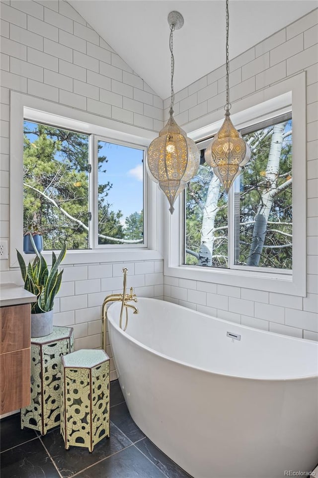 full bathroom with lofted ceiling, a soaking tub, tile walls, and vanity