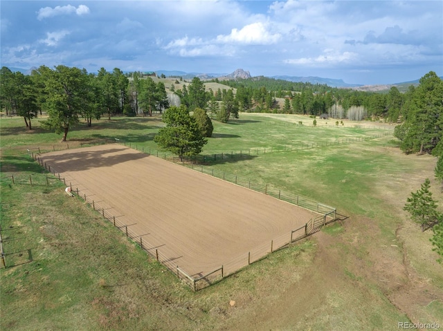view of property's community with a rural view, an enclosed area, fence, and a mountain view